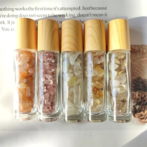 Five glass essential oil bottles with natural wood caps and colorful crystal stones