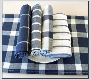 Close-up of blue and white waffle weave tea towels rolled on a white ceramic plate