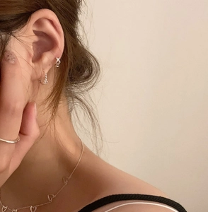 Detail shot of 925 silver jewelry set featuring heart necklace and star earrings on model