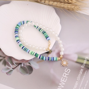 Detail of bohemian double-layer necklace with pearls, clay beads, and golden star pendant