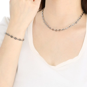 Détail d'un ensemble collier et bracelet argenté à maillons grains de café sur mannequin