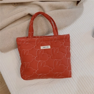 Close-up of red quilted tote bag featuring white rabbit embroidery and Simple Wish label