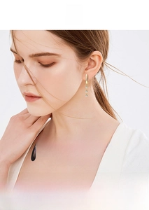 Detail of elegant gold tassel earrings with three vertically aligned sparkling crystals