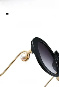 Close-up of retro round sunglasses with gold metal temples and large pearl accents