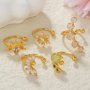 Detail of five 18k gold ear cuffs with green and white zircon stones in floral patterns