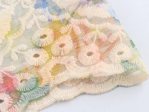 Detail der Blumenstickerei und des bunten Druckstoffs auf dem französischen Kleid