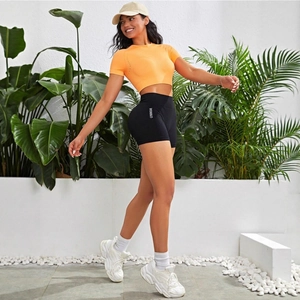 Women's summer athletic set featuring orange crop top and black yoga gym shorts