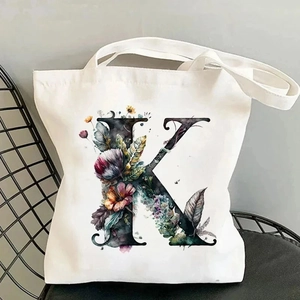 Detailed view of canvas tote bag with floral letter K print on a black chair