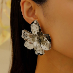 Close-up of oversized silver textured flower earring with artistic hammered petal details