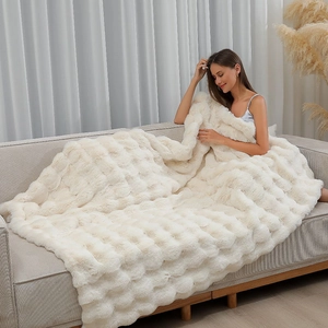 Detail of white plush faux fur blanket with cubic quilting used on a sofa