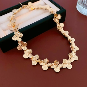 Detail of golden clover flower necklace featuring adjustable chain and metal clasp