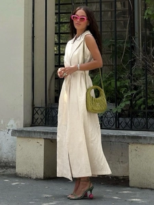 Full street style view of beige sleeveless linen dress with lapel collar and waist belt