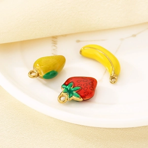 Detailed macro shot of enamel fruit charms including banana, strawberry, and mango pendants
