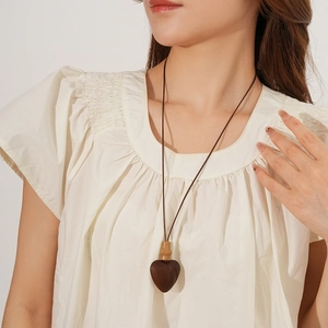 Detail of wooden heart pendant with bamboo accents on a vintage style cord necklace