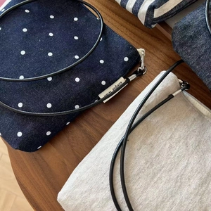 Close-up of denim polka dot and linen crossbody phone bags on a wooden desk