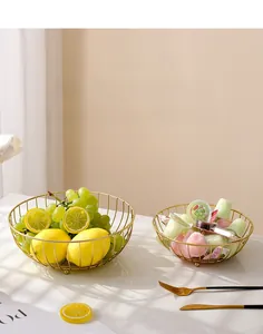 Detail of two golden iron fruit baskets in different sizes on a marble surface