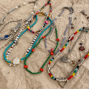 Detail of layered Y2K beaded necklaces with butterfly heart charms and flower pendants