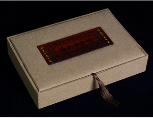 Detail of a vintage Chinese gift box featuring a carved wood insert and silk tassel