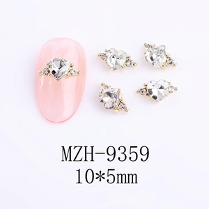 Macro view of heart-shaped gold nail gems with mini rhinestones on a pink nail tip