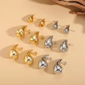 Macro shot of gold and silver spiral stud earrings set on a warm beige background
