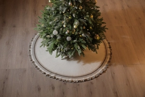 Knitted Christmas tree skirt with beige base, brown geometric patterns, and fringed ruffle