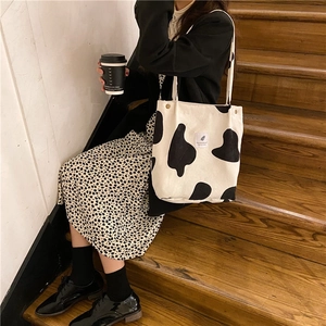 Detalle del bolso tote de pana con estampado de vaca y botón a presión en entorno real