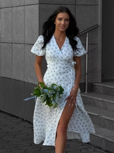 Detail of high-slit hem on white cotton floral dress with blue blossom patterns