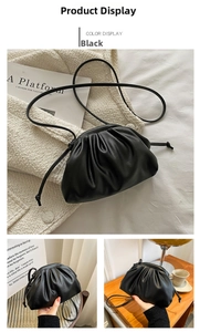 Detail of a soft black pleated cloud clutch bag with magnetic closure and slim shoulder strap