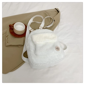 Detalle de mochila de felpa blanca con bordado Good Luck sobre tejido de piel sintética