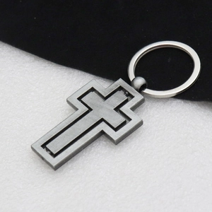 Detail shot of the rotating vintage silver metal cross keychain on dual-tone background