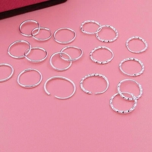 Detail of smooth and twisted S999 sterling silver hoop earrings on a soft pink surface