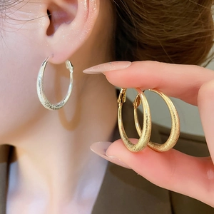 Gros plan détaillé de boucles d'oreilles créoles rondes mates et givrées en or et argent