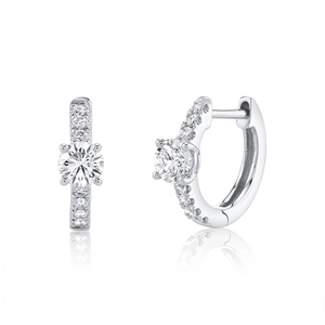 Macro shot of silver huggie earrings with a large center stone and pavé diamond detailing