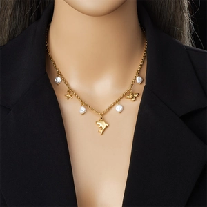 Elegant gold ocean themed necklace with dolphin starfish and white pearls worn by model