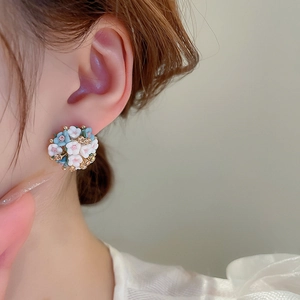 Macro view of blue and white cluster flower earrings with crystals on female model