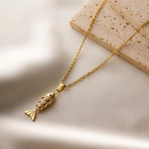 Detailed close-up of a champagne gold fish pendant with red gemstone eyes on silk