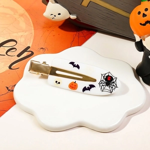 Close-up of Halloween duckbill hair clips with pumpkin and spider web motifs