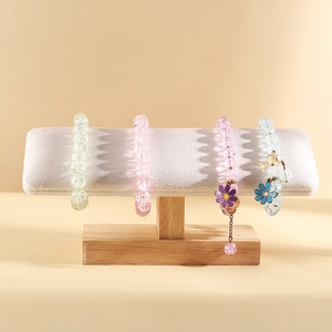 Solid wood jewelry stand showcasing pastel beaded bracelets with daisy pendants
