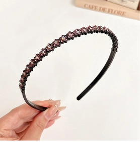 Detail shot of a black headband with delicate purple rhinestone flowers on a white base
