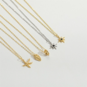 Detail view of gold and silver starfish and shell pendant necklaces on white surface