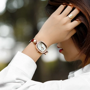 Elegant rose gold square watch with crystal bezel and red leather strap on wrist