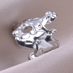 Macro shot of liquid metal style irregular ring on elegant champagne satin fabric