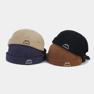 Close-up of corduroy brimless hats in four colors with mountain embroidery and adjustable straps