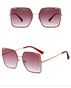 Dettaglio di occhiali da sole oversize quadrati con montatura dorata e lenti sfumate rosse