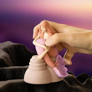 3D mermaid aromatherapy candle sitting on a rock base with soft pink tones