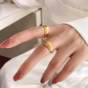 Detail of layered gold rings with wave patterns and rope texture on model's hand