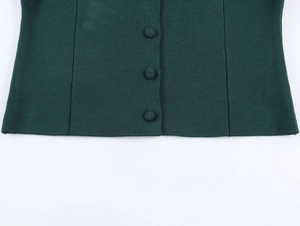 Detailed view of dark green knit cardigan hem with matching fabric covered buttons