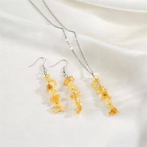 Detail view of yellow natural stone necklace and earrings set on white silk background