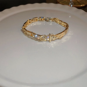 Macro view of gold plated belt buckle bracelet with pavé cubic zirconia and safety chain