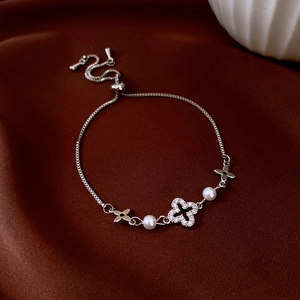 Close-up of adjustable silver clover bracelet with zircon pavé and white pearls on silk